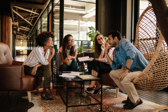 Three co-workers onlooking as one talks up an idea in a modern workplace.