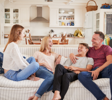 Family cuddled together on a couch, laughing and cutting up.