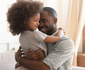 Smiling father embracing his school-age daughter.